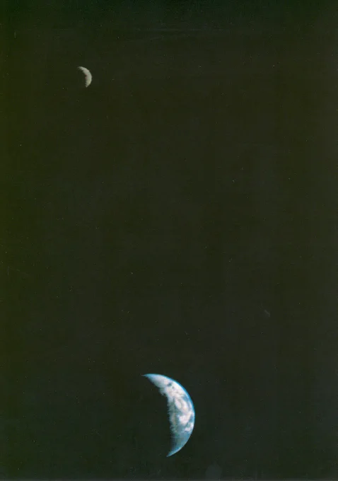 A crescent Earth (bottom) and faint grey Moon (top left) are seen together in the blackness of space in this image taken by Voyager 1 on September 18, 1977. Credit: NASA/JPL