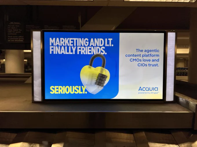 Digital billboard showing an ad for Acquia, highlighting marketing and IT collaboration with a padlock image and bold text.