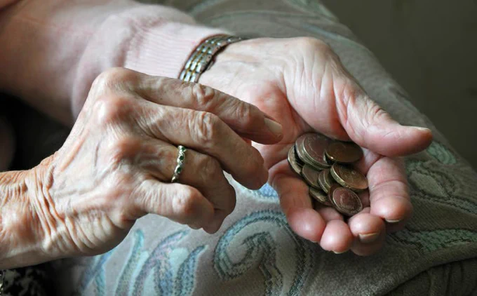 A pensioner holding some coins in their hand, only their hands are visible in the picture